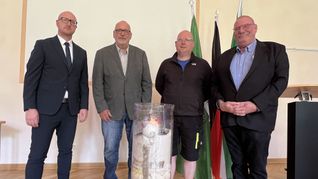 Schleidens Bürgermeister Ingo Pfennings (v.li.) nahm die Wanderkerze in Empfang, die Klaus Jansen, HaJo Meier und Udo Kraatz nach ins Rathaus gebracht haben. Auf ihr sind die Namen der Flutopfer vermerkt. Foto: Michael Nielen
