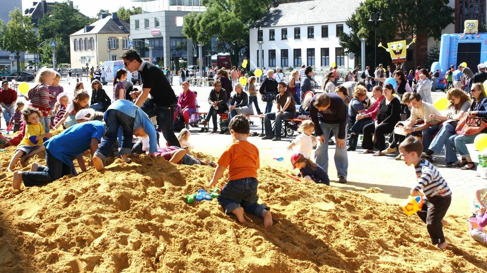 Der Riesen-Sandkasten auf dem Viehmarkt ist ein beliebter Treffpunkt für Familien mit Kleinkindern, die hier nach Herzenslust wühlen, buddeln und Freunde treffen können. Einen Überblick über die vielfältigen Spielaktionen bietet hier der Infostand der City-Initiative. Foto: Archiv