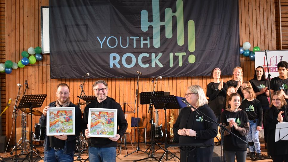 Sebastian Dzienudda-Pesch (links) und Timo Mattes (rechts) aus dem Vorstandsteam des gemeinnützigen Vereins erhalten als Dankeschön ein kleines Präsent.