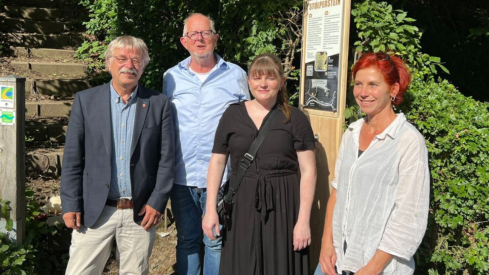 Klaus Onasch (stellvertretender Bürgermeister), die Initiatoren Ben Magrean und Katharina Isabel Franke sowie Ulrike Meissner von der Schreinerei Holzart präsentieren die Holztafel, die auf den Stolperstein an der Dreilägerbachtalsperre in Roetgen hinweist.