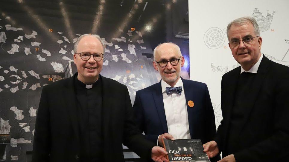 Bischof Dr. Stephan Ackermann, Museumsdirektor Markus Groß-Morgen und Dompropst Weihbischof Jörg Peters bei der Ausstellungseröffnung vor einem Bild der Altarinsel von oben.