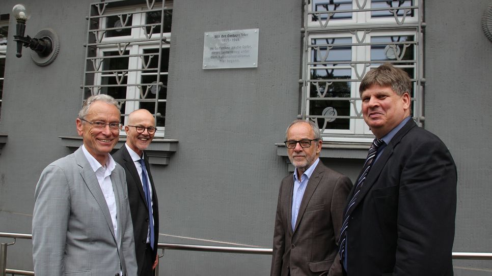 Dr. Jürgen Brauer (Generalstaatsanwalt a. D.), Peter Fritzen (Leitender Oberstaatsanwalt), Klaus Jensen (ehemaliger Oberbürgermeister der Stadt Trier) und Dr. Thomas Grotum (Historiker der Universität Trier) freuen sich, dass die Gedenktafel wieder am Gebäude der Christophstraße 1 hängt