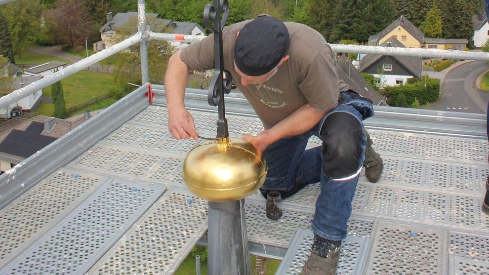 Frank Mertens befestigte den Wetterhahn so, dass er sich wieder im Wind drehen kann.