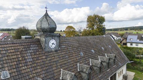 Das Ziffernblatt der historische Zwiebelturmuhr auf dem Dach der alten Schule in Antweiler erstrahlt nach einer Restaurierung in neuem Glanz.