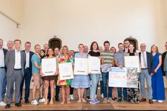 Das Foto zeigt die Sieger mit Staatssekretär Andy Becht (rechts) und Mosel-Weinkönigin Marie-Sophie Schwarz, den Preisstiftern sowie den Vertretern der Wettbewerbsträger im Kulturzentrum Kapuzinerkloster Cochem.