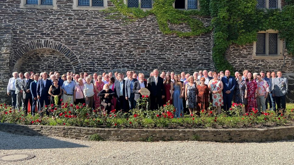 Im Rosenhof der Reichsburg Cochem versammeln sich Stadtbürgermeister Walter Schmitz, Siegfried Schmitz und weitere Ehrengäste zu einem feierlichen Gruppenfoto nach der Wappentellerverleihung.