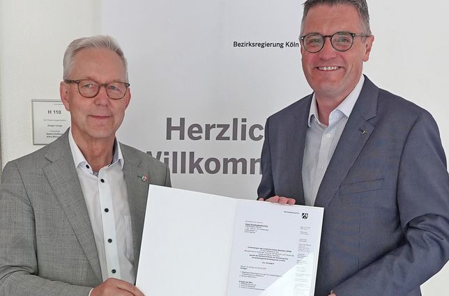Der Kölner Regierungspräsident Gregor Lange und Städteregionsrat Dr. Tim Grüttemeier mit dem Förderbescheid.