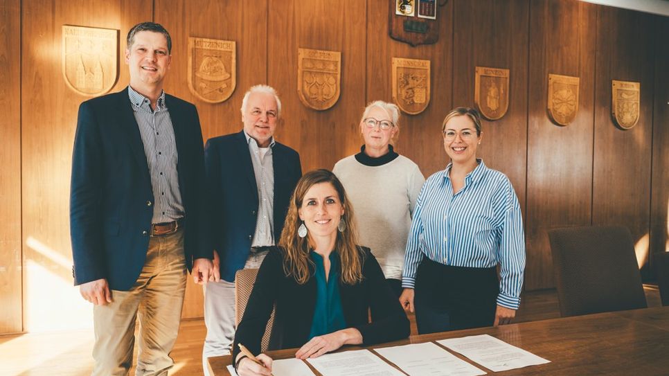 Bürgermeisterin Dr. Carmen Krämer unterzeichnet die Entwicklungsvereinbarung im Beisein von NRW.URBAN-Geschäftsführer Henk Brockmeyer und Projektleiter Klaus-Dieter Büttner, Monika Liedtke, Bauverwaltung der Stadt Monschau sowie Tanja Fischer, Projektteam seitens NRW.URBAN (v.l.).