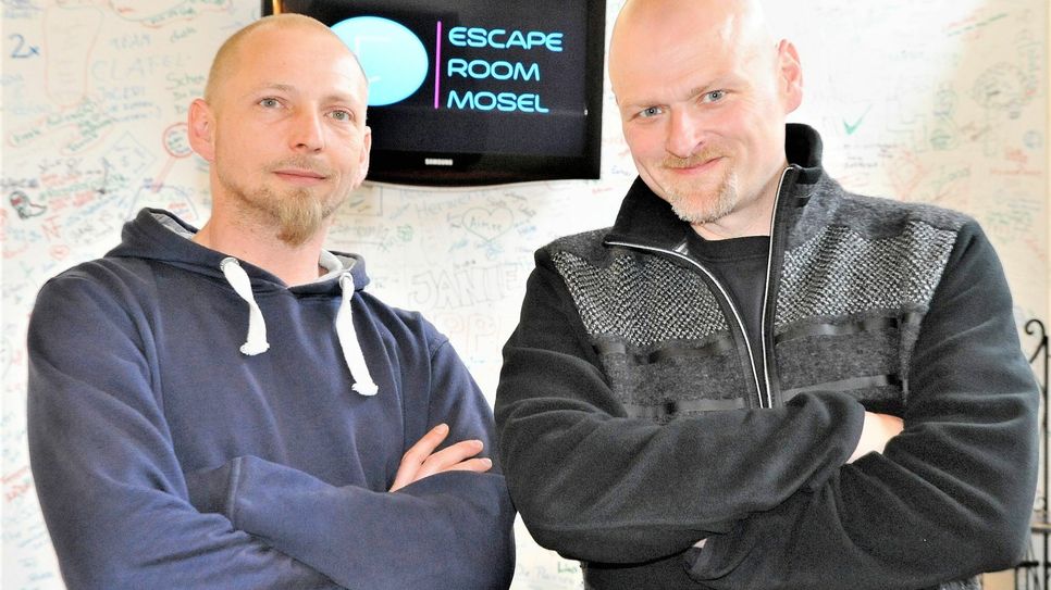 Alexander Wagner (rechts) und Andre Hild-Dreiocker, die Gamemaster des Escape-Rooms-Mosel, vor Wänden mit Graffiti-Eindrücken ihrer Gäste.                      Foto: Ursula Schmieder